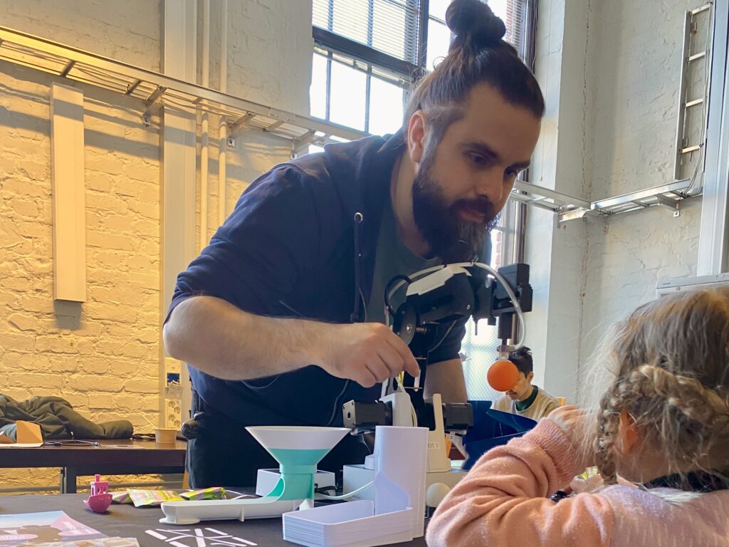 Pieni käsivarsirobotti, jonka äärellä on aikuinen mies ja pieni tyttö.